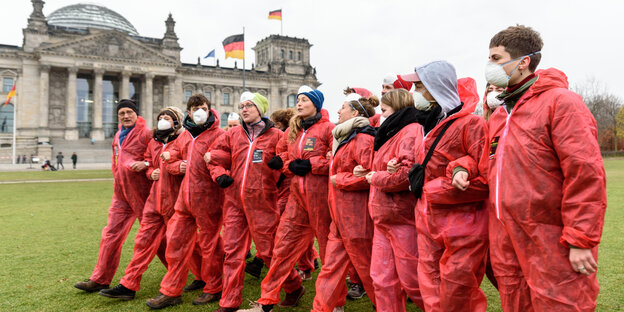 in rot gekleidete AktivistInnen bilden eine Kette vor dem Reichstag