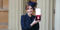 Rowling hält stolz eine schatule mit einem Orden in der Hand und lächelt in die Kamera