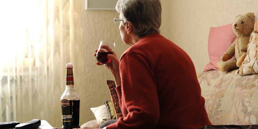 Frau in Rückenansicht mit Alkohol-Flasche