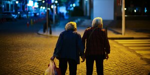 Zwei ältere Menschen stehen Hand in Hand an einer Straßenkreuzung