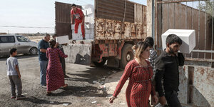Zwei Frauen zwei Jungen und zwei Männer nehmen von einem frewilligen Helfer Hilfsgüter von einem Lastwagen entgegen