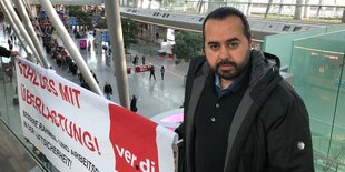 Özay Tarim vor einem Transparent am Flughafen