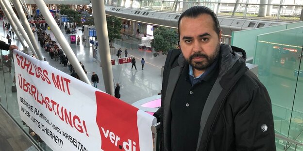 Özay Tarim vor einem Transparent am Flughafen