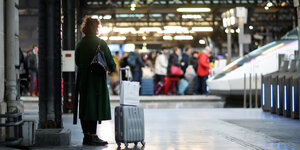 Eine Reisende wartet mit Koffer auf einem Bahnsteig am Gare de l'Est in Paris