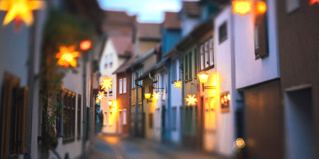 Eine Gasse mit niedrigen Häusern, die Weihnachtssterne als Schmuck haben