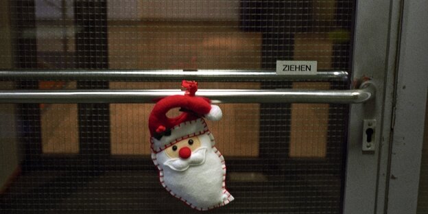 Ein Kuschel-Weihnachtsmannkopf hängt an einer Tür