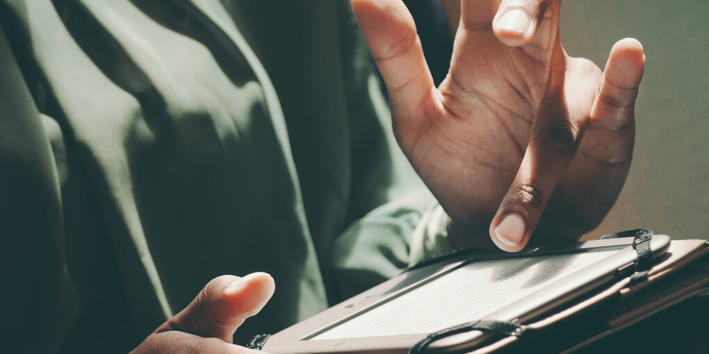 Hand tippt auf einem kleinen Tablet