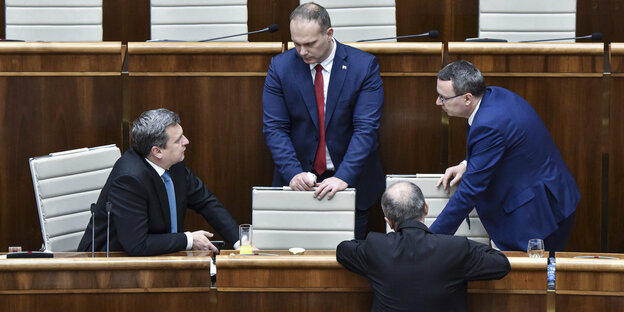 Vier Männer diskutieren in einem Sitzungssaal