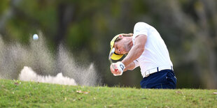 Mann schlägt mit einem Golfschläger einen Ball