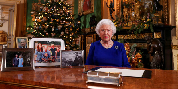 Die Queen, recht steif, zwischen Kamin und Familienfotos