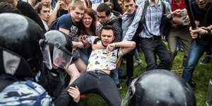 Mann in Moskau fast am Boden umringt von starker Polizei und Menschen die ihm helfen wollen
