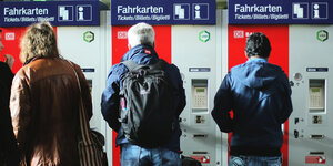 Die Rückansicht von drei Personen vor Fahrkartenautomaten