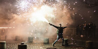 Mann rennt mit Feuerwerk in der Hand an Silvester über eine Brücke in Berlin kreuzberg.
