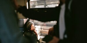 Eine Frau sitzt im Zug, sie sieht versunken aus