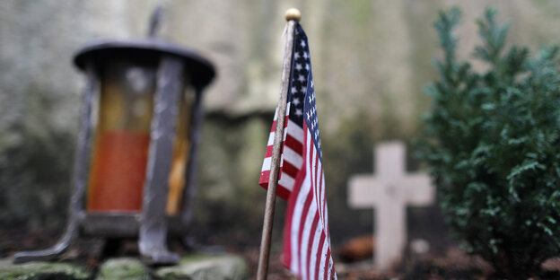 US-Fahne vor Kreuz und Grablicht