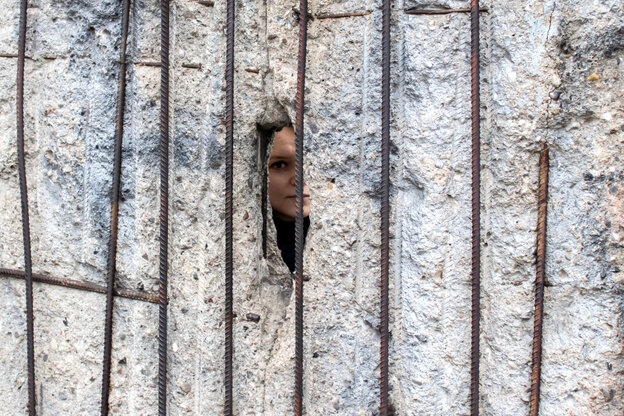 ein Gesicht schaut durch ein Loch in der Mauer