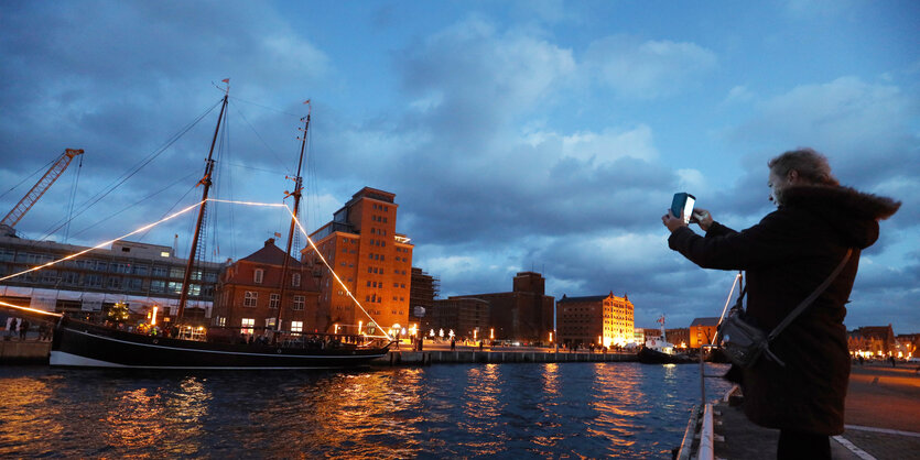 Eine Passantin fotografiert Schiffe, die aus dem Alten Hafen in Wismar auslaufen.