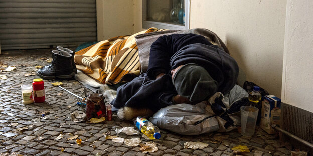 Obdachloser Mensch liegt auf dem Boden