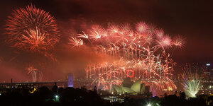 Das Feuerwerks auf der Hafenbrücke in Sydney leuchtet in roten Farben.