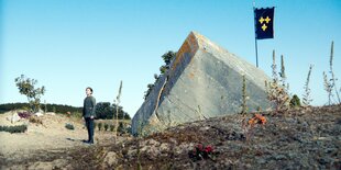 Ein junges Mädchen in Uniform neben einem Betonbunker und Blumen geschmückten Umgebung