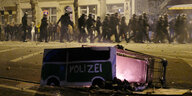 Leipzig: Polizisten räumen eine Kreuzung im Stadtteil Connewitz, während im Vordergrund ein Einkaufswagen liegt, auf dem das Wort Polizei zu lesen ist