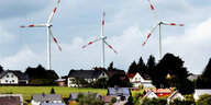 Windräder des Windparks Schöneseiffen drehen sich hinter Wohnhäusern in Gemünd in der Eifel
