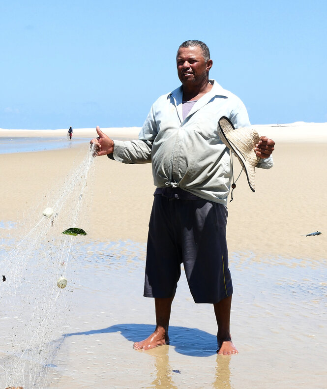 Ein Mann steht am Strand mit einem Fischernetz in der Hand