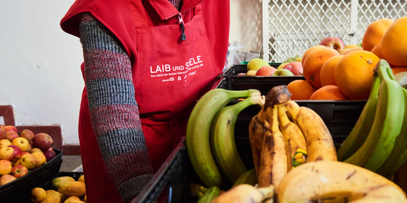 Eine Person steht hinter einem Korb von Bananen