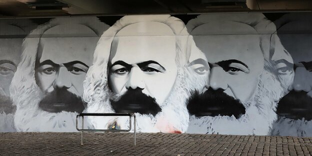 mehrere übereinandergelagerte Karl-Marx-Porträts in schwarz-weiß auf einer Betonwand