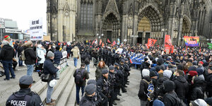 Eine Polizeikette zwischen Demonstarnten vor dem Kölner Dom