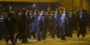 Polizisten rennen im Stadtteil Connewitz in Leipzig auf der Straße. Sie tragen Schutzmontur.