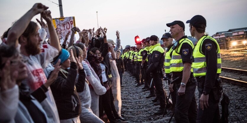 Demonstranten und Polizisten stehen sich in einer Reihe gegenüber