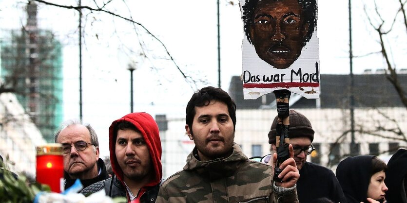 ein Mann hält ein gemaltes Protrait von Oury Jalloh während einer Demonstration