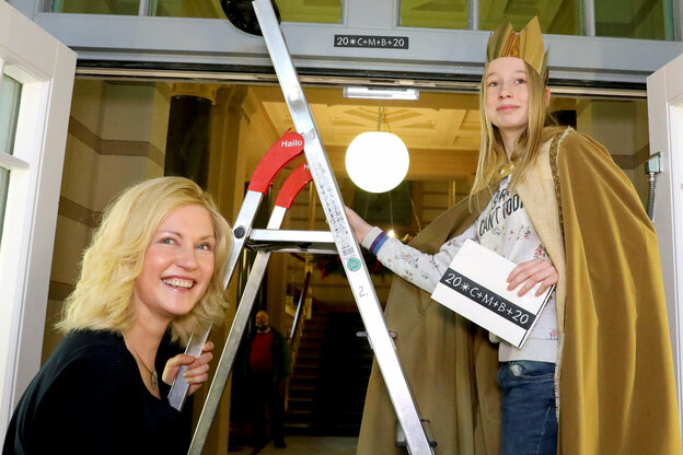 Kind mit Krone auf Leiter bringt ein Schild über einer Tür an, daneben steht eine Frau, es ist Manuela Schwesig, Ministerpräsidentin von Mecklenburg-Vorpommern