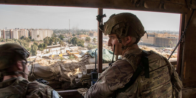 Zwei Soldaten stehen auf einem Beobachtungsstand und blicken über Bagdad