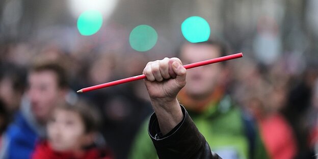 Ein Demonstrant hält einen überlangen Stift in seiner Faust