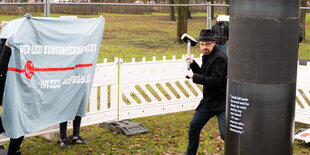 Ein Mann schwingt einen Hammer gegen die Stele