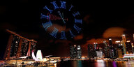 Hafenansicht von Singapur - darüber bilden das Zifferblatt einer Uhr