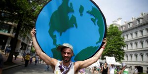Ein Mann trägt eine gemalte Weltkugel auf seinen Schultern