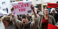 Frauen protestieren, eine Frau hält ein Transparent mit der Aufschrift "We believe you"