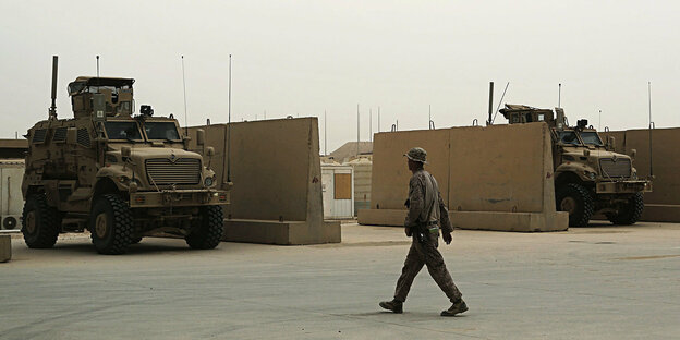 Ein Soldat geht an Miltärfahrzeugen vorbei