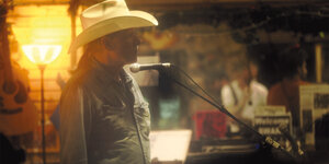 Der Musiker Michael Gira mit Cowboyhut vor einem Mikro