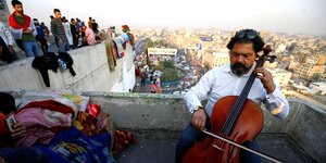 Ein mann spielt auf dem Dach eines Hauses Cello