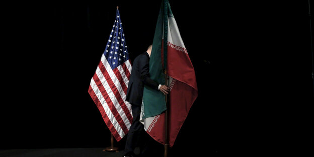 Amerikanische und iranische Flagge, dazwischen ein Mann im Anzug