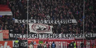 Fußballfans mit Transparenten: „Gegen das Vergessen, Antisemitismus bekämpfen“