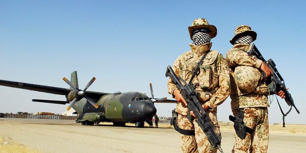 Zwei Bundeswehrsoldaten mit Waffen vor einer Transallmaschine in Afghanistan.