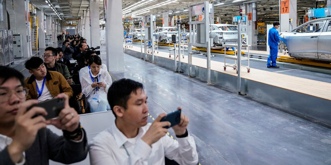 Menschen fotografieren Fließbandarbeiter in der Autoproduktion