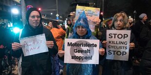 Menschen stehen bei einem Protest mit Schildern in der Hand auf der Straße