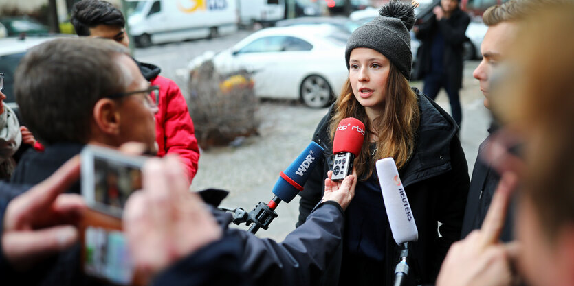 Eine Frau protestiert mit einem Schild und zugeklebten Mund gegen Siemens