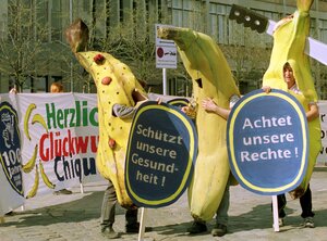 Drei als Bananen verkleidete Demonstranten halten Schilder hoch Drei als Bananen verkleidete Demonstranten halten Schilder hoch